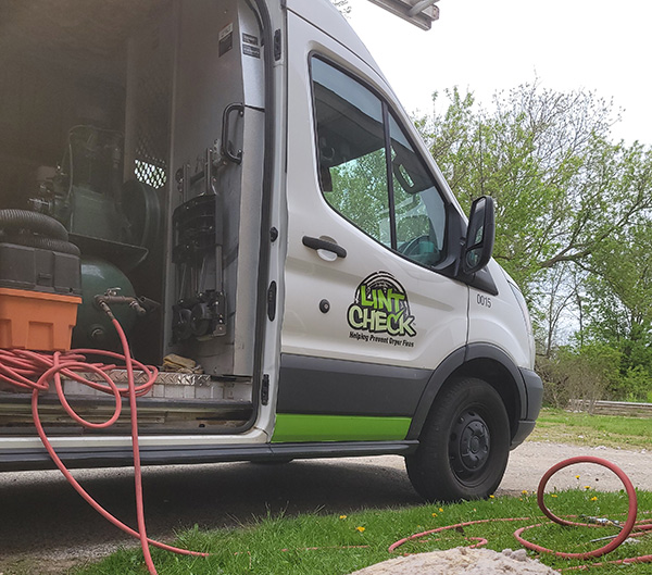 Lint Check Van parked in a driveway with the door open and equipment showing inside.